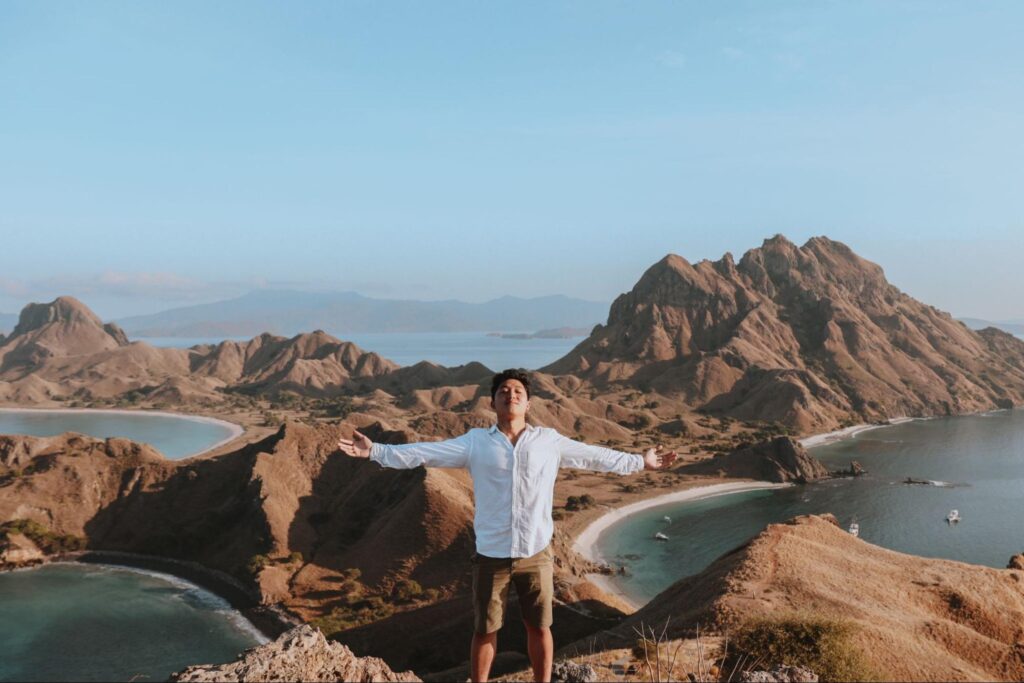 Wisatawan berdiri di puncak Pulau Padar dengan latar panorama Taman Nasional Komodo dari ketinggian